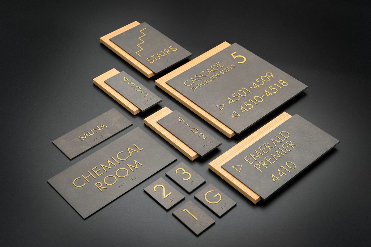 Black and gold thermoformed sign system for luxury resort including floor directory, amenity identification, and unit numbering